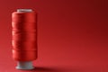 Spool of colorful sewing thread on red background, space for text Royalty Free Stock Photo