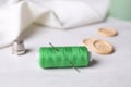 Spool of green sewing thread with needle, thimble and buttons on white table Royalty Free Stock Photo