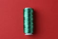 Spool of green sewing thread on red background, top view Royalty Free Stock Photo
