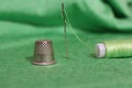 Spool of Green Thread, Thimble and Needle on Green Fabric Royalty Free Stock Photo