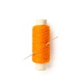 Spool of orange thread with needle isolated on white
