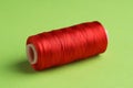 Spool of red sewing thread on green background Royalty Free Stock Photo