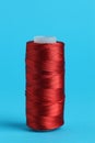 Spool of red sewing thread on light blue background Royalty Free Stock Photo
