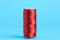 Spool of red sewing thread on light blue background Royalty Free Stock Photo