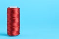 Spool of red sewing thread on light blue background, space for text Royalty Free Stock Photo