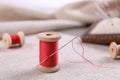 Spool of red sewing thread with needle on fabric Royalty Free Stock Photo