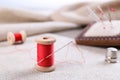Spool of red sewing thread with needle on white fabric Royalty Free Stock Photo