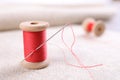 Spool of red sewing thread with needle on white fabric, closeup Royalty Free Stock Photo