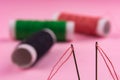 Spool with red thread and needle on pink background Royalty Free Stock Photo