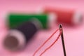 Spool with red thread and needle on pink background Royalty Free Stock Photo