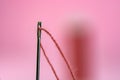 Spool with red thread and needle on pink background Royalty Free Stock Photo