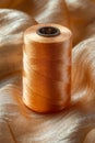 A spool of thread sitting on top of a gold fabric Royalty Free Stock Photo