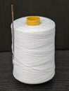 A spool of white thread with a needle isolated on black background Royalty Free Stock Photo