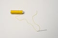 Spool of yellow thread with a needle threaded with thread on a white background Royalty Free Stock Photo