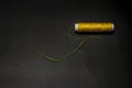 Spool of yellow thread with a threaded needle on a black background Royalty Free Stock Photo
