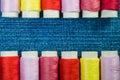 Spools of colored sewing thread arranged in two rows on blue denim with copy space Royalty Free Stock Photo