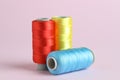 Spools of colorful sewing threads on pink background, closeup Royalty Free Stock Photo