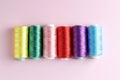Spools of colorful sewing threads on pink background, flat lay Royalty Free Stock Photo