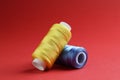 Spools of colorful sewing threads on red background, closeup Royalty Free Stock Photo