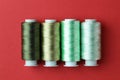 Spools of colorful sewing threads on red background, flat lay Royalty Free Stock Photo