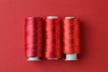 Spools of colorful sewing threads on red background, flat lay Royalty Free Stock Photo