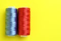 Spools of colorful sewing threads on yellow background, top view. Space for text Royalty Free Stock Photo