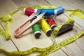 Spools of thread and basic sewing tools including pins, needle, a thimble, a tape measure and yarn scissors on a wooden table Royalty Free Stock Photo