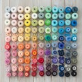 Spools of thread and buttons arranged on a wooden surface display an array of color Royalty Free Stock Photo