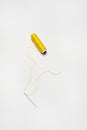 Spools of yellow thread with a needle threaded with thread of the same color on a white background Royalty Free Stock Photo