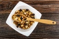 Spoon in bowl with cereal breakfast with peanut and raisin on wooden table. Top view