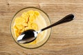 Spoon in bowl with corn flakes and yogurt on wooden table. Top view Royalty Free Stock Photo