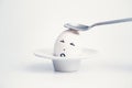 Spoon breaks sad egg on a stand in the form of human head . Royalty Free Stock Photo