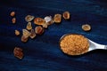 Spoon with brown cane sugar on a blue wooden board, spilled large crystals of brown sugar around