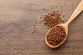 Spoon with buckwheat tea granules on wooden table, top view. Space for text