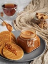A spoon with carmel sauce pours wafers on a plate. Close-up. Jar of homemade caramel sauce. Selective Focus, Vertical Orientation Royalty Free Stock Photo