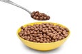 Spoon with chocolate cereal balls over bowl with cereal balls on white Royalty Free Stock Photo