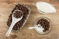 Spoon, corn chocolate balls in transparent plate, corn balls, spoon with yogurt in bowl, sauce boat with yogurt on table. Top view