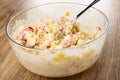 Spoon, crab sticks salad in transparent bowl on wooden table Royalty Free Stock Photo