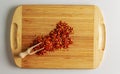 Spoon with crushed dry red chili peppers on a wooden kitchen board Royalty Free Stock Photo