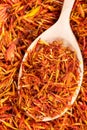 Spoon with dried safflower petals close up on pile