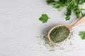 Spoon with dry parsley and space for text on white wooden background Royalty Free Stock Photo