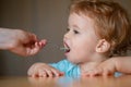 Spoon feeding baby. Mother giving healthy food to her adorable child at home. Feeding kids. Royalty Free Stock Photo