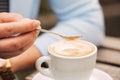 Spoon in a female hand pouring sugar into her coffee cup