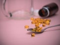 Spoon with fish oil pills. Cod Liver Oil Capsules on spoon on pink background.