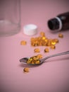 Spoon with fish oil pills. Cod Liver Oil Capsules on spoon on pink background. Royalty Free Stock Photo