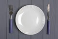 Spoon, fork, grey plate on a gray wooden background Table setting concept Royalty Free Stock Photo
