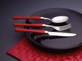 Spoon, fork and knife on a black plate