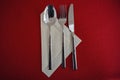 Spoon, fork and knife on a paper napkin and a red tablecloth, table set with copy space, high angle view from above Royalty Free Stock Photo