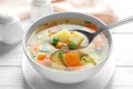 Spoon of fresh homemade vegetable soup over full bowl on white wooden table, Royalty Free Stock Photo