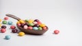 a spoon full of colorful candies on a white table top with scattered scattered candy beans on the table top, with a spoon full of Royalty Free Stock Photo